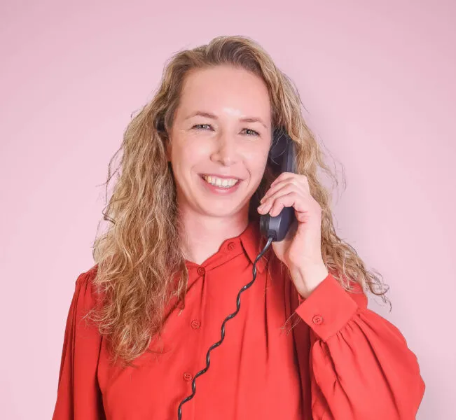 Een medewerker van het Adviesteam van Pleyade houdt een telefoon in haar hand. Telefonisch is zij bereikbaar.