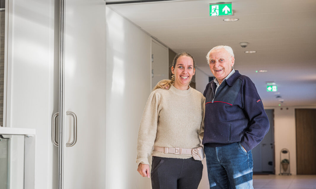 Medewerker en bewoner samen op de gang.