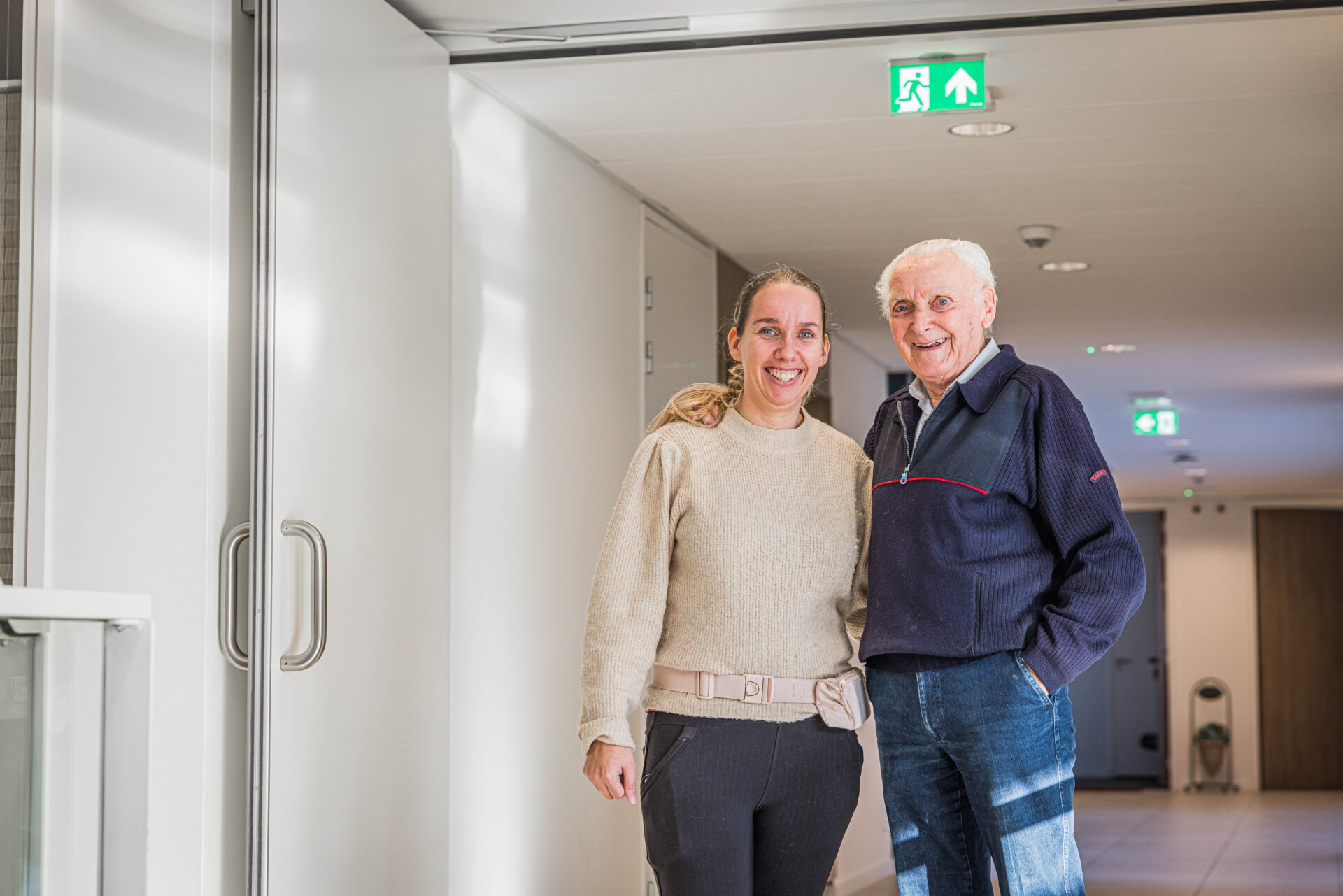 Medewerker en bewoner samen op de gang.