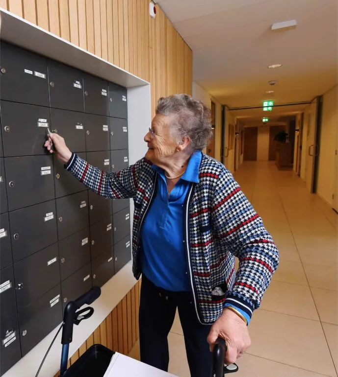 Mevrouw in de gang bij brievenbus