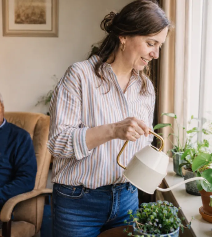Een zorgprofessional geeft de planten water bij een client